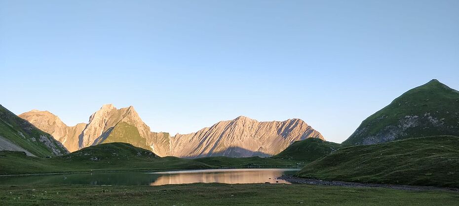 Foto zu dem Thema Grundsätze zur ganzeihtlichen Selbsterfahrung. Ein See im Hintergrund die Berge